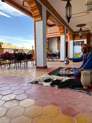 a man sitting on the floor of a patio at Kasbah La Famille Berbère in Boumalne