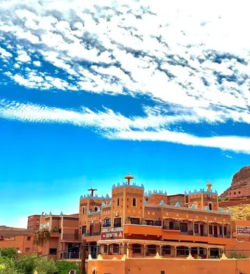 an orange building with a blue sky and clouds at Kasbah La Famille Berbère in Boumalne
