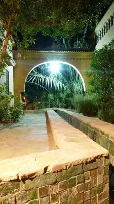 a stone walkway with an arch in a garden at night at Le Chant Des Palmiers in Agdz