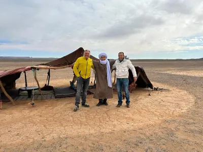 three people standing in front of a tent in the desert at Original Desert Camp in Merzouga