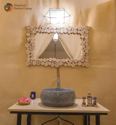 a bathroom with a sink and a mirror on a wall at Original Desert Camp in Merzouga