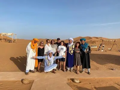 a group of people posing for a picture in the desert at Original Desert Camp in Merzouga