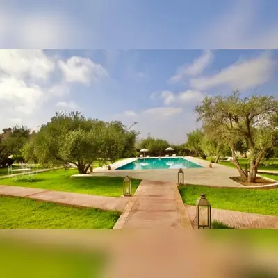 a swimming pool in a park with trees and grass at Upupa de l’Atlas in Marrakech