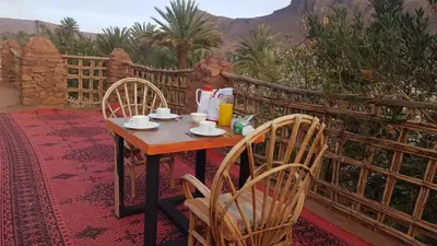 a wooden table with chairs and a table with drinks on it at ecolodge bivouac des aigles in Ouarzazate