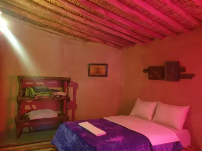 a small bedroom with a bed with pink sheets at ecolodge bivouac des aigles in Ouarzazate