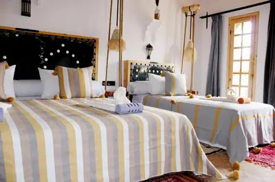 a bedroom with two beds with striped sheets at Dar Mezyana Dades in Aït Idaïr