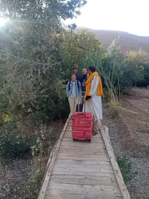 a group of people walking on a wooden path with a suitcase at Dar Mezyana Dades in Aït Idaïr