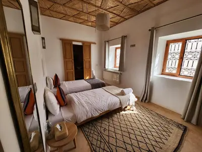 a bedroom with a large bed in a room with windows at AdaZen Ecolodge - Ait Bouguemez in Azilal