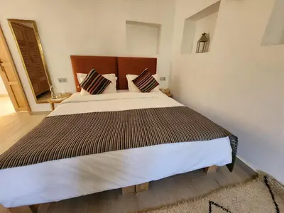 a bedroom with a large bed with a wooden headboard at AdaZen Ecolodge - Ait Bouguemez in Azilal