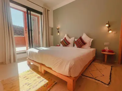 a bedroom with a bed with white sheets and a window at AdaZen Ecolodge - Ait Bouguemez in Azilal