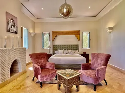 a bedroom with a bed and two chairs and a fireplace at Privat Villa in Marrakesch with Pool & Garten in Marrakech