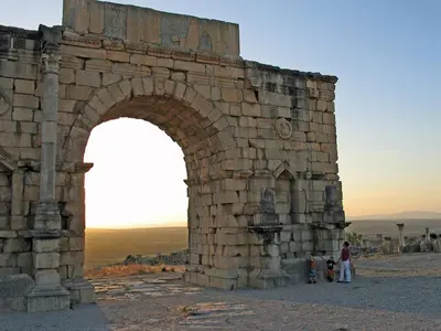 a group of people standing under a stone archway at ferme Walila in Douar Doukkara