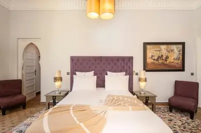a bedroom with a large bed with two chairs at Superbe Villa Y - Calme & sureté - Piscine privée & gouvernante in Marrakech