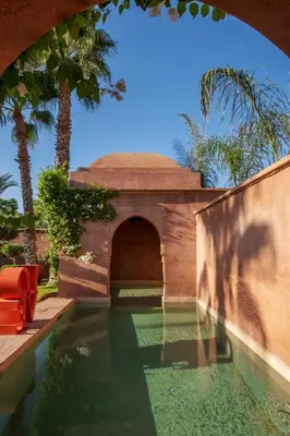 a swimming pool with a fountain in a backyard with palm trees at Superbe Villa Y - Calme & sureté - Piscine privée & gouvernante in Marrakech
