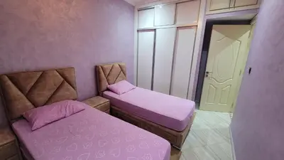 two beds in a room with purple walls at ZR Comfort in Fès