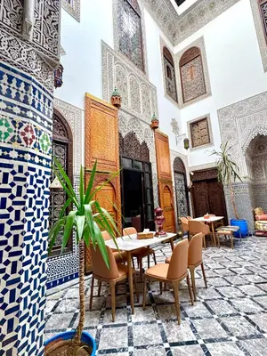 a dining room with a table and chairs in a building at Riad Pacha Palace in Fès