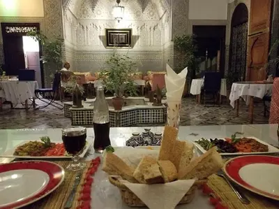 a table with plates of food and a bottle of soda at Riad Pacha Palace in Fès