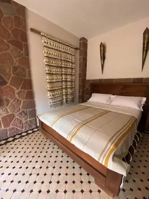 a bedroom with a bed and a stone wall at Boutique Guesthouse Dar Zohra in Marrakech