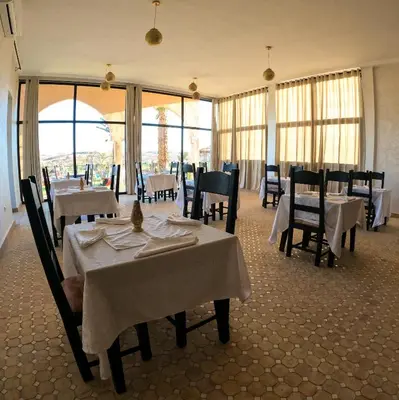a restaurant with white tables and chairs and windows at kasbah yu palace in Ouarzazate