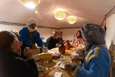 a group of people sitting around a table eating at Bivouac Erg Chegaga Nomademoi in El Gouera