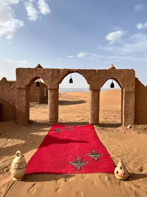 a red blanket sitting in the middle of the desert at Bivouac Erg Chegaga Nomademoi in El Gouera