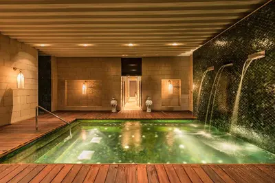 a swimming pool in a building with a fountain at Hotel Sahrai in Fès
