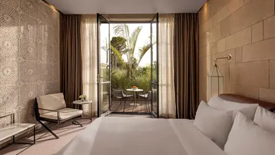 a bedroom with a bed and a chair and a balcony at Hotel Sahrai in Fès