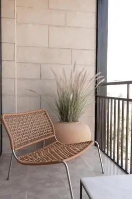 a rattan chair sitting on a balcony with a plant at Hotel Sahrai in Fès