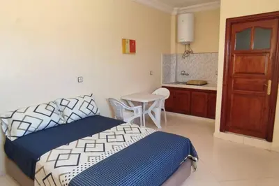 a bedroom with a bed and a table and a kitchen at Studio @khémisset in Khemisset