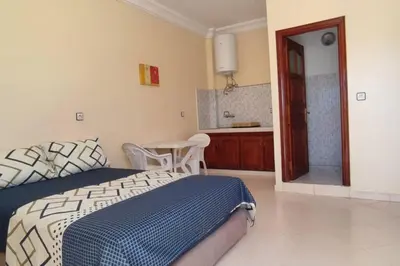a bedroom with a bed and a table and a bathroom at Studio @khémisset in Khemisset