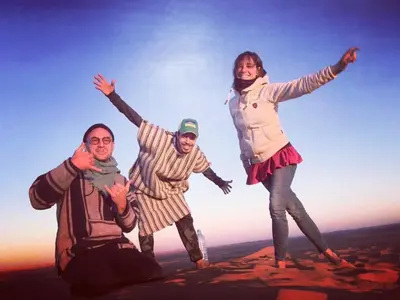 a group of three people standing on top of a mountain at Desert Backpackers Camp in Merzouga