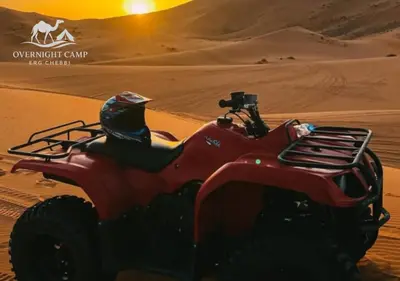 a person riding a red atv in the desert at Overnight Camp Erg Chebbi in Merzouga