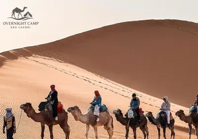 a group of people riding horses in the desert at Overnight Camp Erg Chebbi in Merzouga
