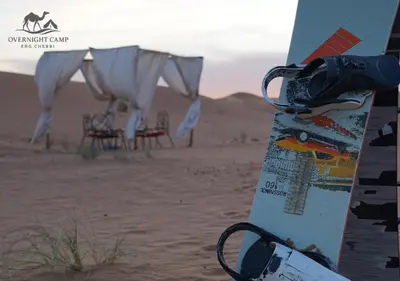 a snowboard sitting in the sand in the desert at Overnight Camp Erg Chebbi in Merzouga