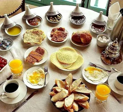 a table with plates of breakfast foods and cups of coffee at dar Benfares rcif in Fès