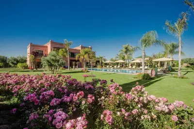 a garden with pink flowers in front of a building at La Villa Rose Anna in Marrakech