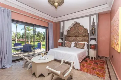 a bedroom with a large bed and a table and chairs at La Villa Rose Anna in Marrakech