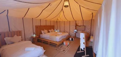 a bedroom with two beds in a tent at Merzouga Bohemian Camp in Merzouga