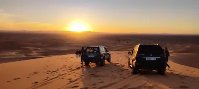 two vehicles parked on a sand dune in the desert at Merzouga Bohemian Camp in Merzouga