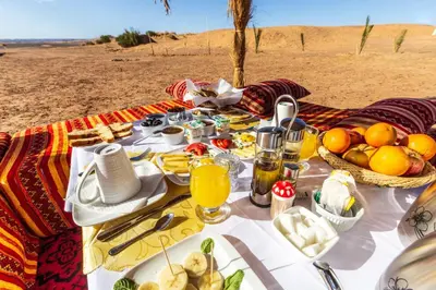 a picnic table with food on the beach at Merzouga Bohemian Camp in Merzouga