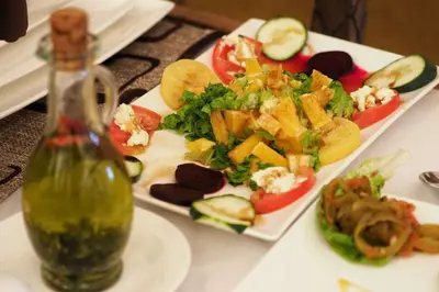 a plate of food with a salad and a bottle of sauce at Merzouga Bohemian Camp in Merzouga