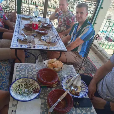 a group of people sitting at a table with plates of food at Palais Fes Yahya - family hosting in Fès al Bali