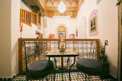 a balcony with a table and two stools at Palais Fes Yahya - family hosting in Fès al Bali