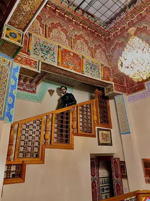 a man standing on a balcony in a room with painted ceilings at Palais Fes Yahya - family hosting in Fès al Bali