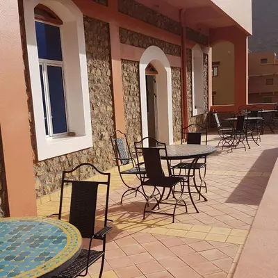 a patio with tables and chairs on a building at Auberge Restaurant Fatihi Freres in Tinerhir