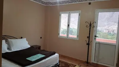a bedroom with a bed and two windows at Auberge Restaurant Fatihi Freres in Tinerhir