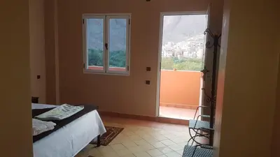 a bedroom with a bed and a large window at Auberge Restaurant Fatihi Freres in Tinerhir