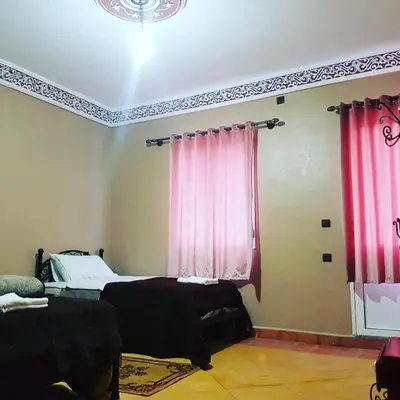 a bedroom with two beds and pink curtains at Auberge Restaurant Fatihi Freres in Tinerhir