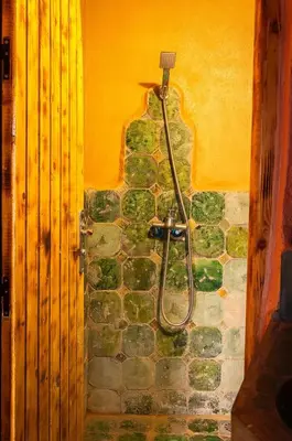 a bathroom with a shower in a stone wall at Auberge Kasbah Dar Sahara Tours in Mhamid