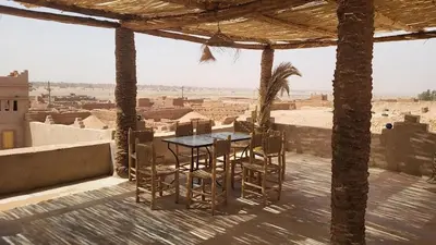 a table and chairs on a balcony with a view of the desert at Auberge Kasbah Dar Sahara Tours in Mhamid